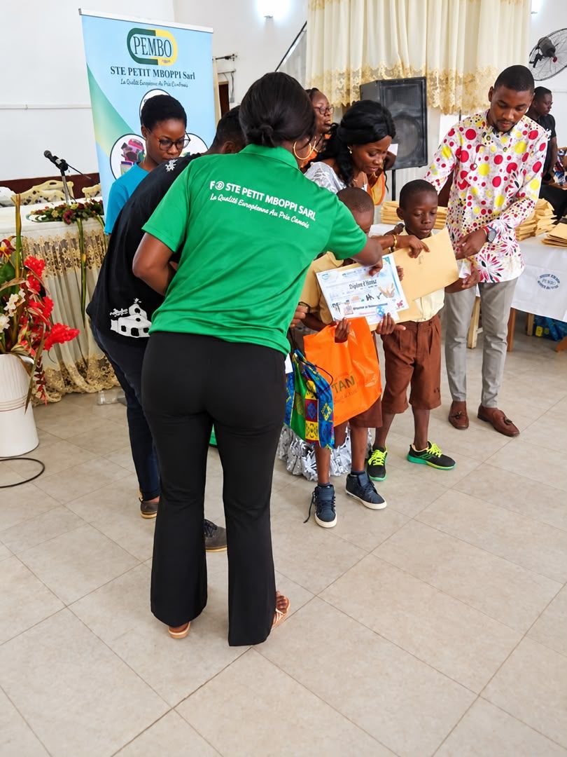 Une collaboratrice PEMBO remet un diplôme d’honneur et un cadeau à de jeunes élèves