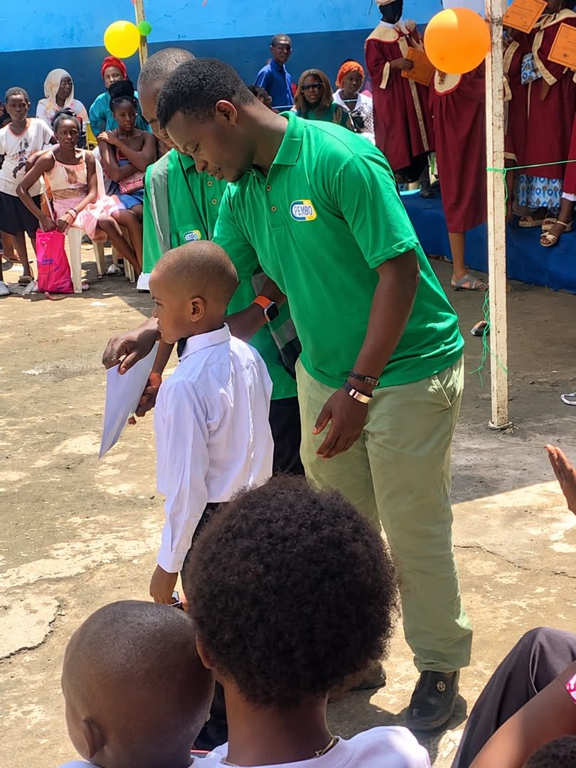 Un collaborateur PEMBO félicite un jeune élève lors d’une remise de prix